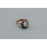 An opal cluster ring in rose yellow metal, size P, unmarked, 2.8gm The centre opal is crazed