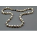 A string of off-round cultured pearls, length 44cm, white metal floral clasp