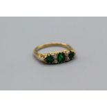 An Edwardian three stone emerald ring. The principal stone approximately 4mm diameter, the