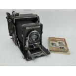 A Graflex Speed Graphic large format folding bellows camera and manual.