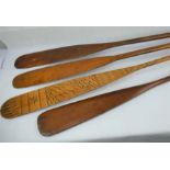 Four vintage wooden boat paddles, one with engraved decoration.