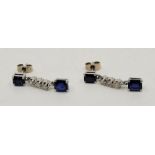 A pair of precious white metal, diamond and sapphire set drop earrings, having emerald cut