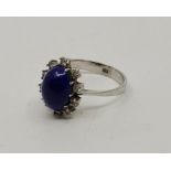 An 18ct. white gold, diamond and lapis lazuli dress ring, set oval cabochon lapis lazuli to centre