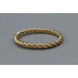 A yellow metal twisted hinged bangle marked 18k Italy. Approximate weight 31.8gm. Cased in a