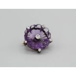 A carved amethyst flower brooch, set with six Old European cut diamonds, in yellow metal (which