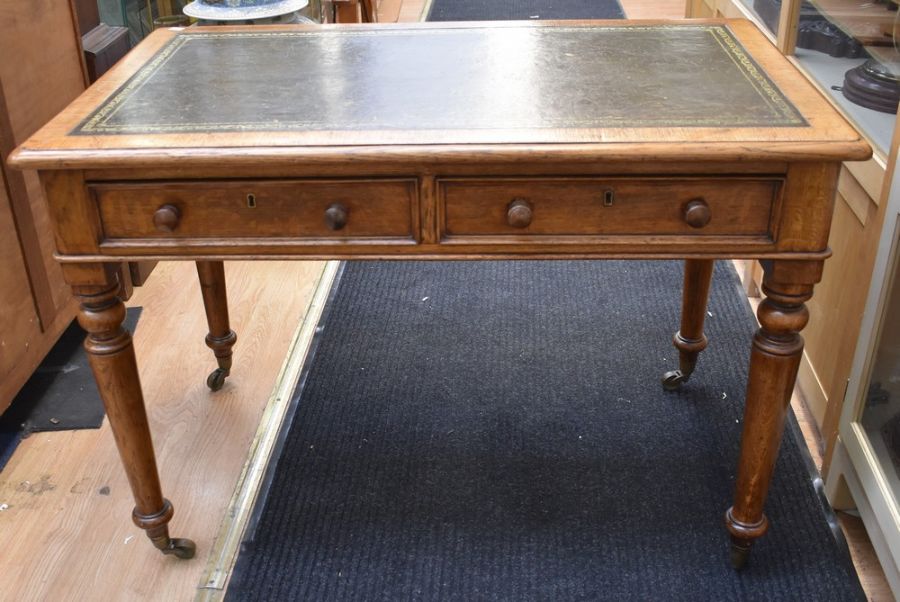 An early 20th century light oak olive green tooled leather topped office desk with four turned