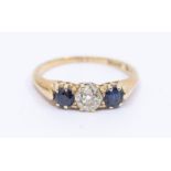 A sapphire and diamond 18ct gold three stone ring, comprising a cushion cut diamond claw set to