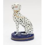 A Staffordshire model of a Dalmatian with a gilt collar and chain, seated on a cobalt blue base,