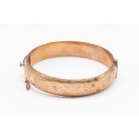 A 9ct gold hinged bangle, hollow form with engraved decoration, width approx 12mm, internal diameter