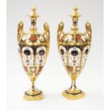 A pair of Royal Crown Derby 1128 Imari twin handled vases, heavily gold painted, cracks to bases