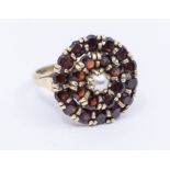 A garnet and pearl set 9ct gold ring, comprising a circular form set with round cut garnets set to