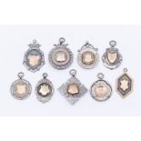 A collection of nine silver fob medallions, various shapes and designs, with gold tone cartouche,