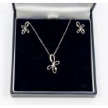 A diamond set 9ct white gold pendant and earrings set, comprising a floral wirework pendant set with