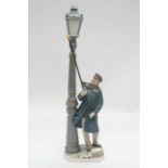 A large Lladro figure of a man lighting a street lamp - 46cm high.