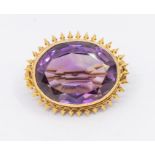 An early 20th century amethyst and gold brooch, oval mixed cut stone within a arrow like border,