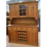 A large antique pine kitchen dresser with a built-in wine rack, three top cupboard doors and a