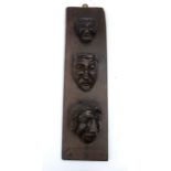 An 18th century carved oak wall hanging, with three carved graduated heads (probably from pieces