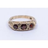 A garnet and diamond 9ct gold ring, set three round garnets, scrolled shoulders, size K, total gross