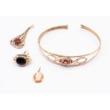 A 9ct gold wire work torque bangle set to the centre with three round mixed cut garnets, width