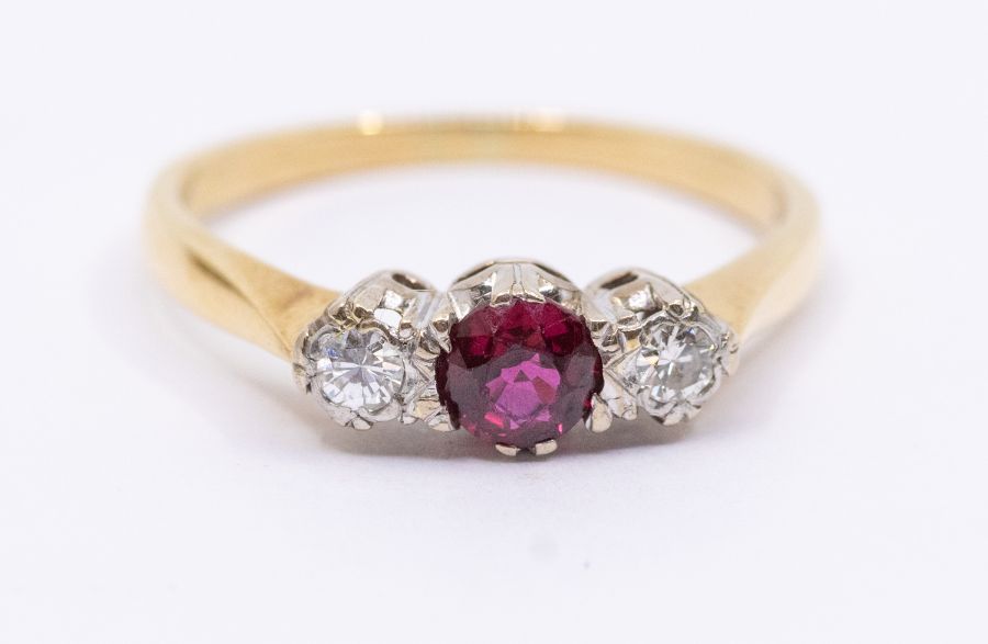 A diamond and ruby three stone 18ct gold, comprising a central round cut ruby, approx 4mm, with