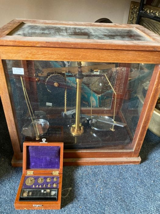Scientific scales and boxed weights with gauges in a glass case.