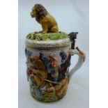 An early 20th Naples porcelain tankard relief moulded with a lion hunt, the hinged cover with lion