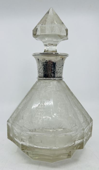 An etched glass decanter, with dodecahedral sides decorated with grape patterns, with a white