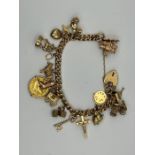 A 9ct gold charm bracelet with a heart padlock clasp. With 14 charms, plus a 1903 half sovereign.