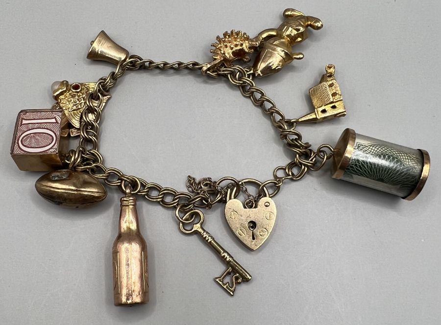 A 9ct gold charm bracelet comprising 11 charms plus padlock clasp. Gross weight approximately 24.4