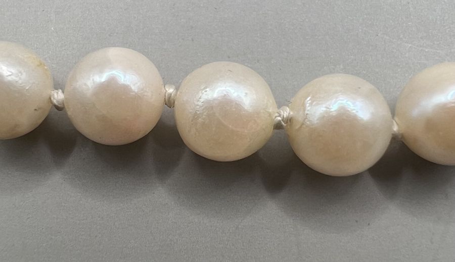 A strand of cream coloured pearls with a greenish pink orient with a 375 stamped clasp. - Image 2 of 3