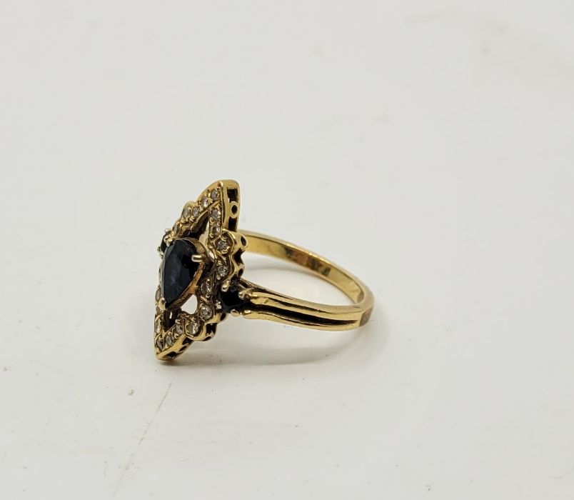 A precious yellow metal, diamond and sapphire set dress ring, having pierced navette form mount