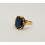 A precious yellow metal and blue paste set cocktail ring, claw set emerald cut blue paste to