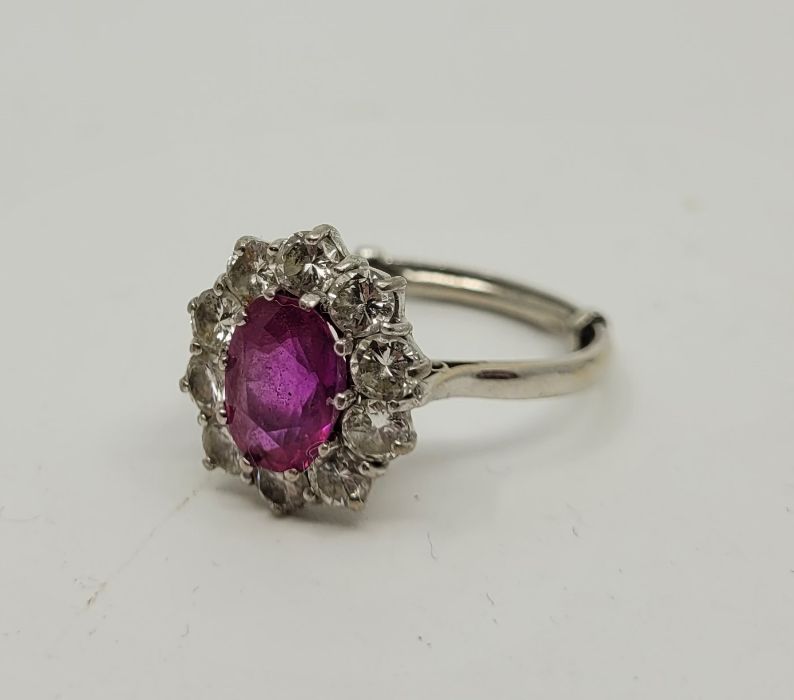 An 18ct. white gold, pink sapphire and diamond cluster ring, set mixed oval cut sapphire bordered by