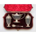 An Edwardian Neo-Classical style silver three piece condiment set to include boat shaped mustard pot
