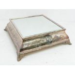 A French style silver plated beveled mirror top cake stand on four scroll feet and engraved