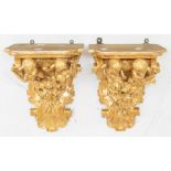 A pair of early 20th Century carved giltwood figural wall brackets, each with a pair of cherubs