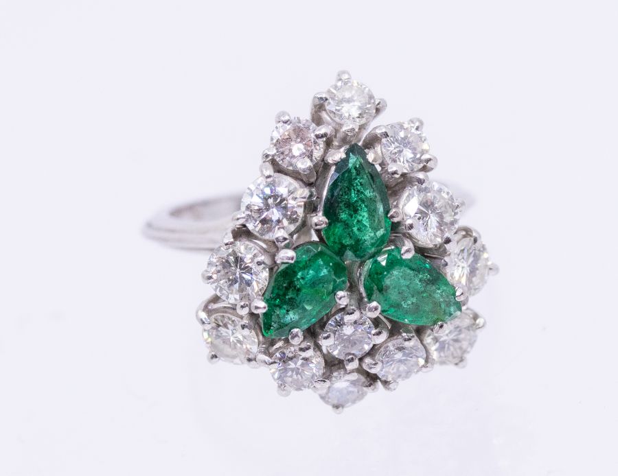 ***AUCTIONEER TO ANNOUNCE SMALL CHIP TO ONE EMERALD*** An emerald and diamond 18ct white gold
