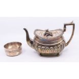 A George III large silver oblong teapot, lobed lower section, on four ball feet, the hinged cover