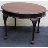 An Edwardian mahogany dining table, the oval top with gadrooned edge, on leaf carved slender