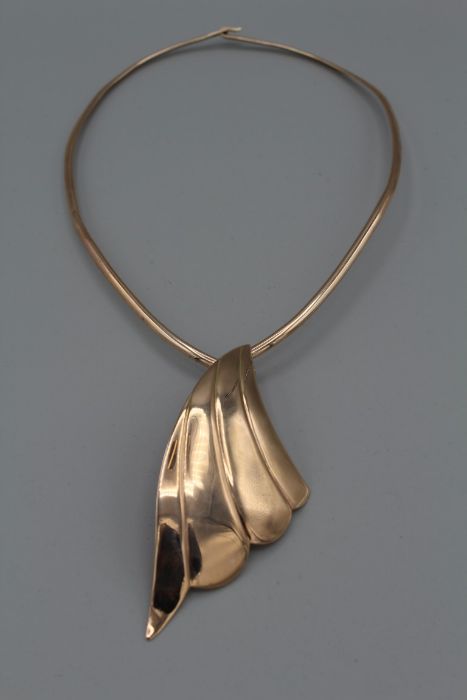 A hand made yellow metal articulated collar with a chunky handmade wave shaped drop, also in