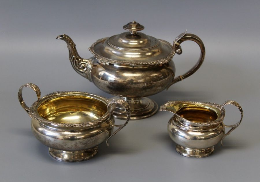 An early 19th century sterling silver footed tea set including bone heat sinks, comprising three