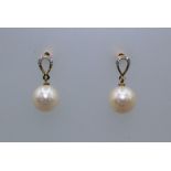 A pair of diamond and round white cultured pearl drop ear studs. The pearls are white with a