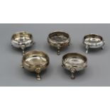 A collection of cauldron shaped five salts, each with three hoofed feet. Four of the pieces are