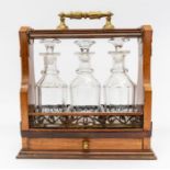 A 19th century three decanter tantalus with ornate brass carrying handle and drawer pull, pierced