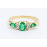 An emerald and diamond 18ct gold ring, comprising a centeral oval emerald approx 4 x 6mm, two