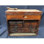 An early 20th century oak tool box with hinged top lid and six pull out drawers, gilt label 'COR' to