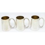 German Silver: A collection of three plain silver tankards with gilt interiors, all with C shaped