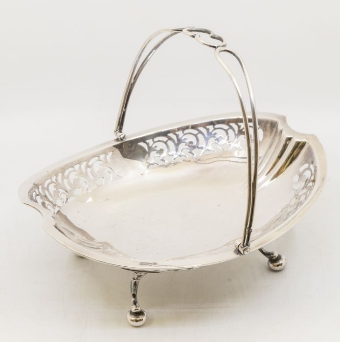 A George V silver basket, shaped oval with wire work swing handle, reticulated side panels, raised
