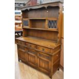 A reproduction oak dining room dresser with linenfold front detail and leaded glass