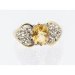 A citrine and diamond 9ct gold ring, comprising an oval claw set cirtine, within open diamond set